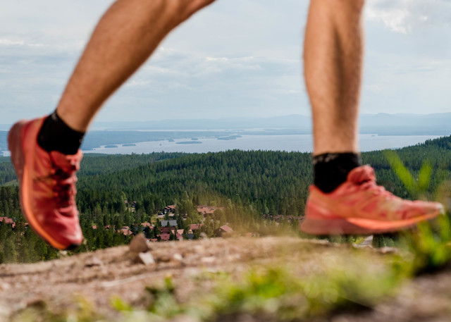 Close-up of a runner with a view of forests and a lake in the background.