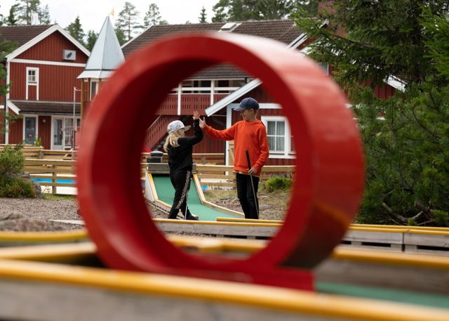 Two children high-five at a mini golf course.