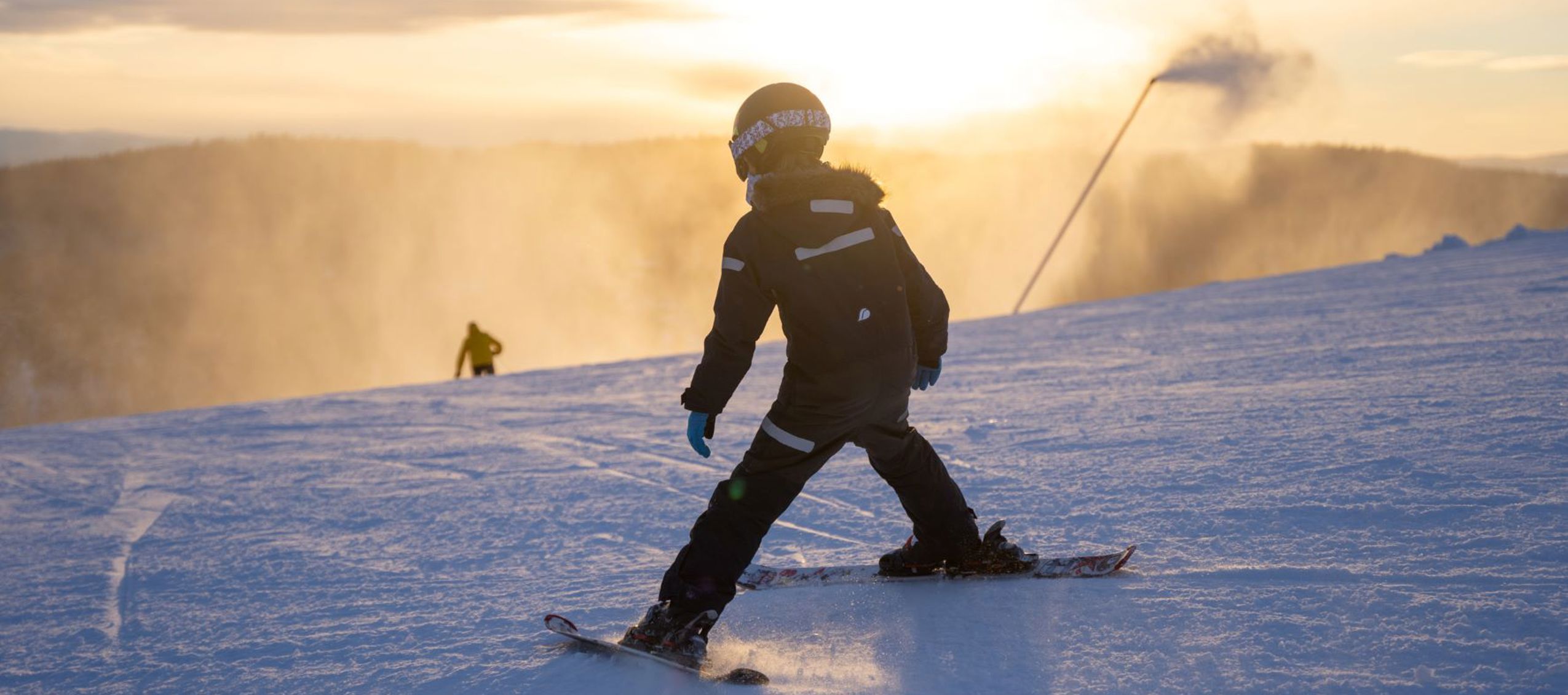 Pojke som åker slalom i solnedgången i Orsa Grönklitt