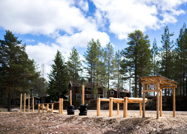 Outdoor gym in a forest setting with wooden ramps and workout equipment.