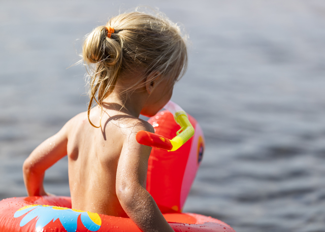 Small child with a swim ring heading into the water.