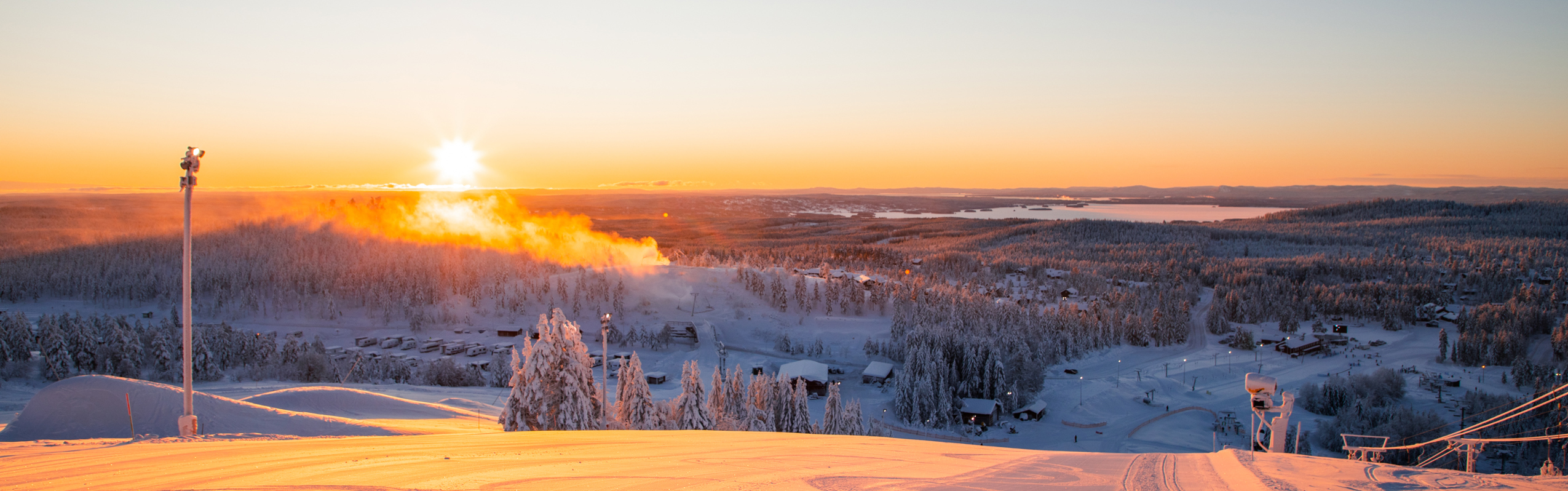 Solnedgång i Orsa Grönklitt över en pistad backe.