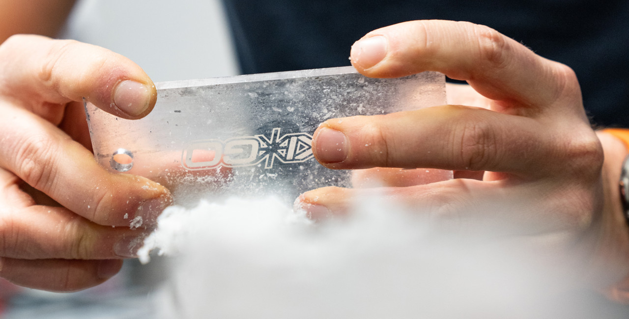 Close-up of hands scraping wax off a pair of cross-country skis.